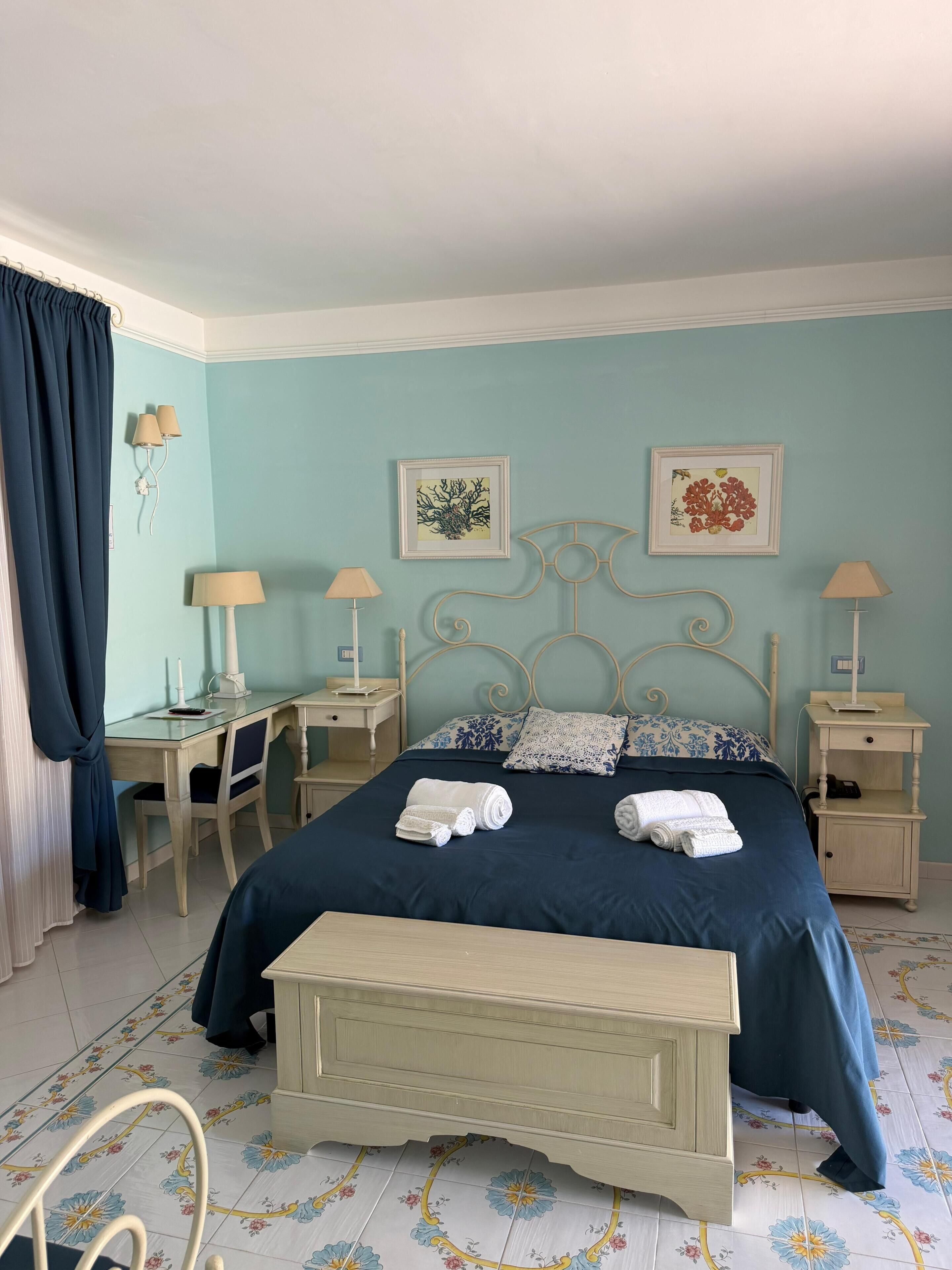 Un dormitorio con cama, mesitas de noche, escritorio y silla.