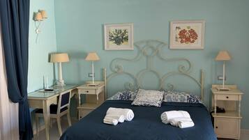 Un dormitorio con cama, mesitas de noche, escritorio y silla.