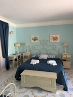 Un dormitorio con cama, mesitas de noche, escritorio y silla.