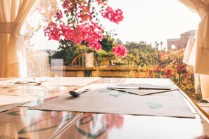 A table with a map and papers, a window with a view of a garden and a building. - Residence Mendolita (Lipari)