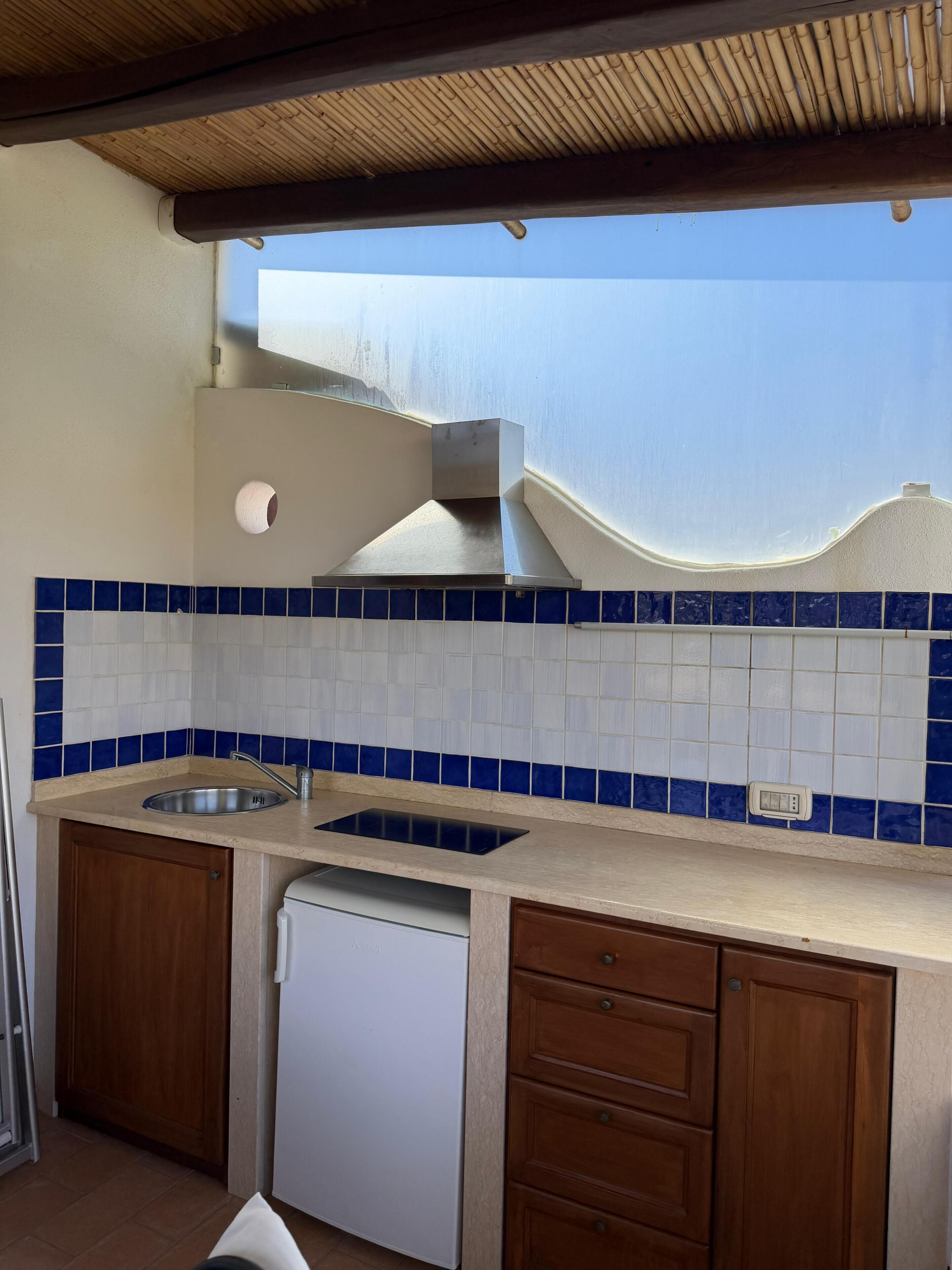 A kitchen with a sink, stove, and wooden cabinets.