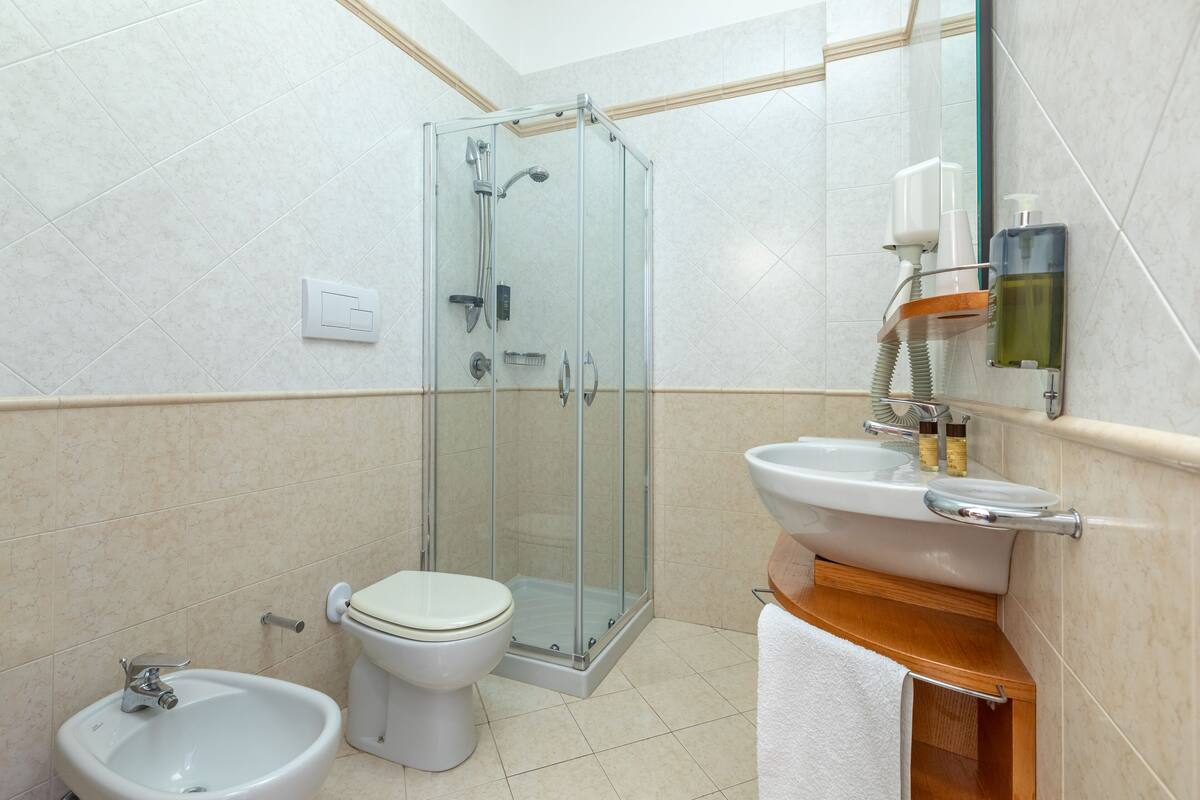 Een moderne badkamer met een douchecabine van glas, een witte wastafel en een toilet.