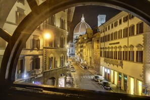A nighttime view of a historic street with buildings, a dome structure in the background, and a bridge. - Soggiorno La Cupola (Florence)