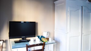 Una habitación con televisión de pantalla plana, cafetera y armario.