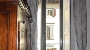 Una habitación con un armario de madera, un radiador, una ventana con cortinas y una planta en el alféizar.