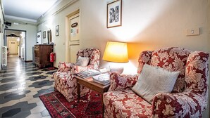En stue med tapetserede sofaer, en lampe og et tæppe.