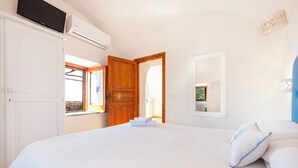 Un dormitorio con una cama grande, un armario de madera, un televisor y una ventana con cortinas.