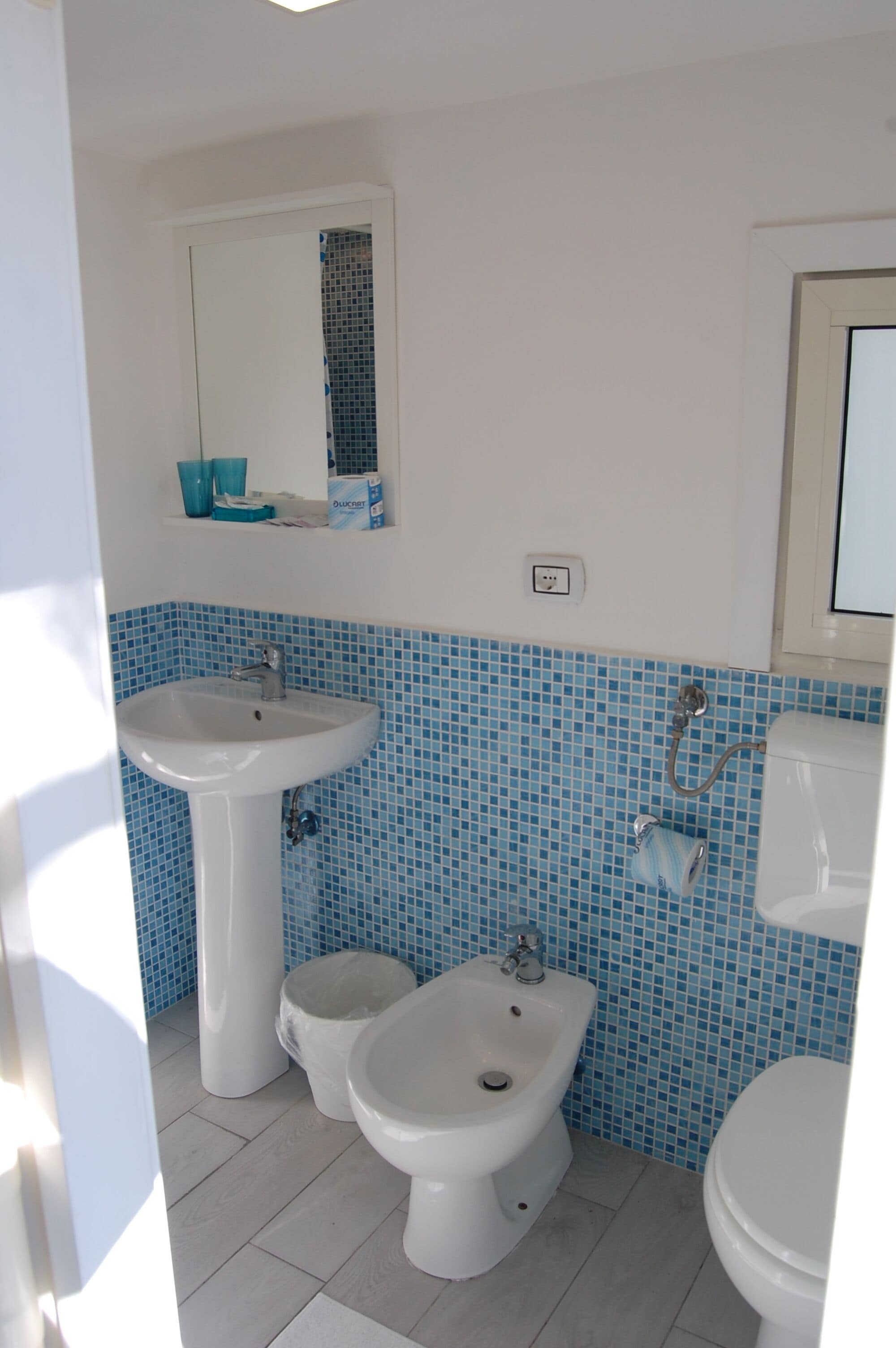 A bathroom with a white sink, bidet, and toilet, tiled in blue and white.