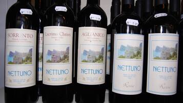 Una fila di bottiglie di vino con etichette che indicano diverse tipologie e le loro origini.