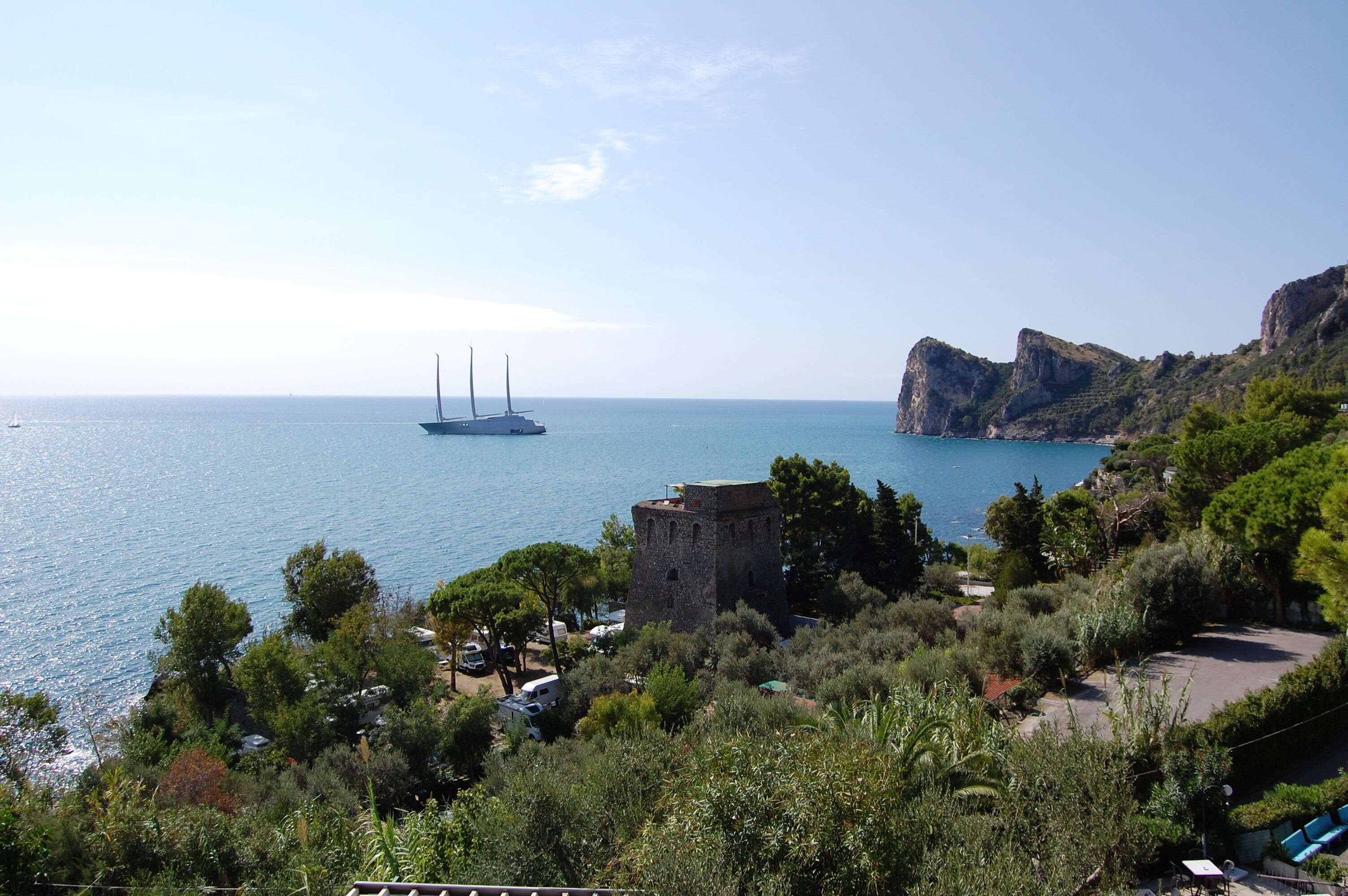 A coastal view with a sailboat, a tower, and rocky terrain.
