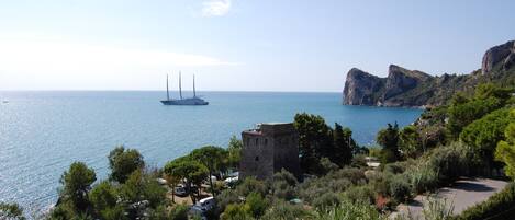 A coastal view with a sailboat, a tower, and rocky terrain.