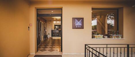 A hotel lobby with a checkered floor, a reception desk, and a staircase leading to an upper level.