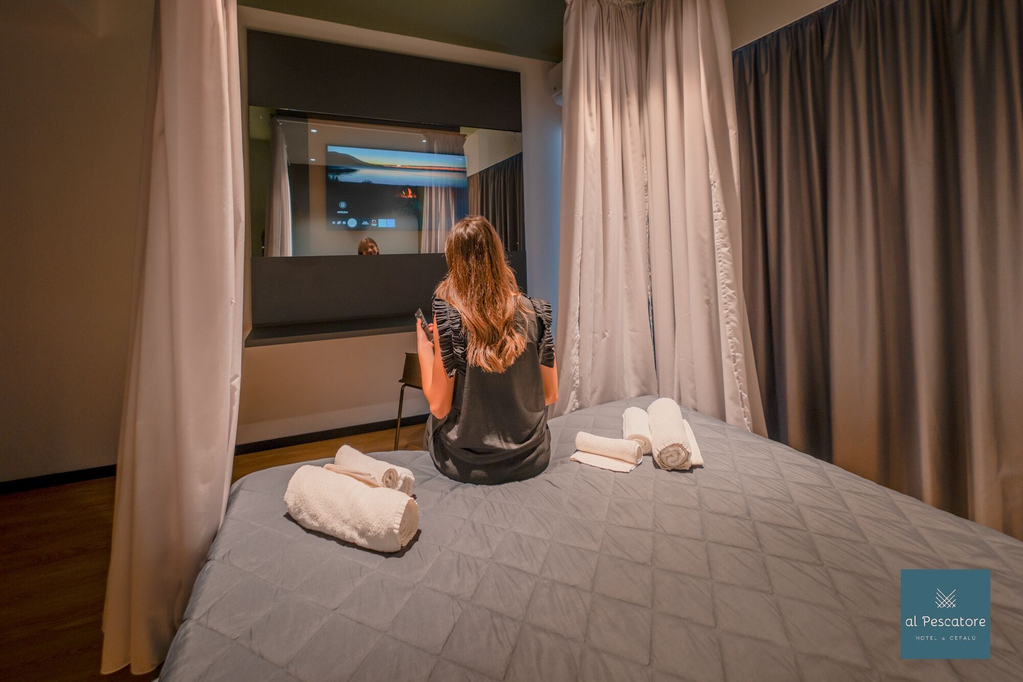 Ein Hotelzimmer mit Bett, Fernseher und Vorhängen.