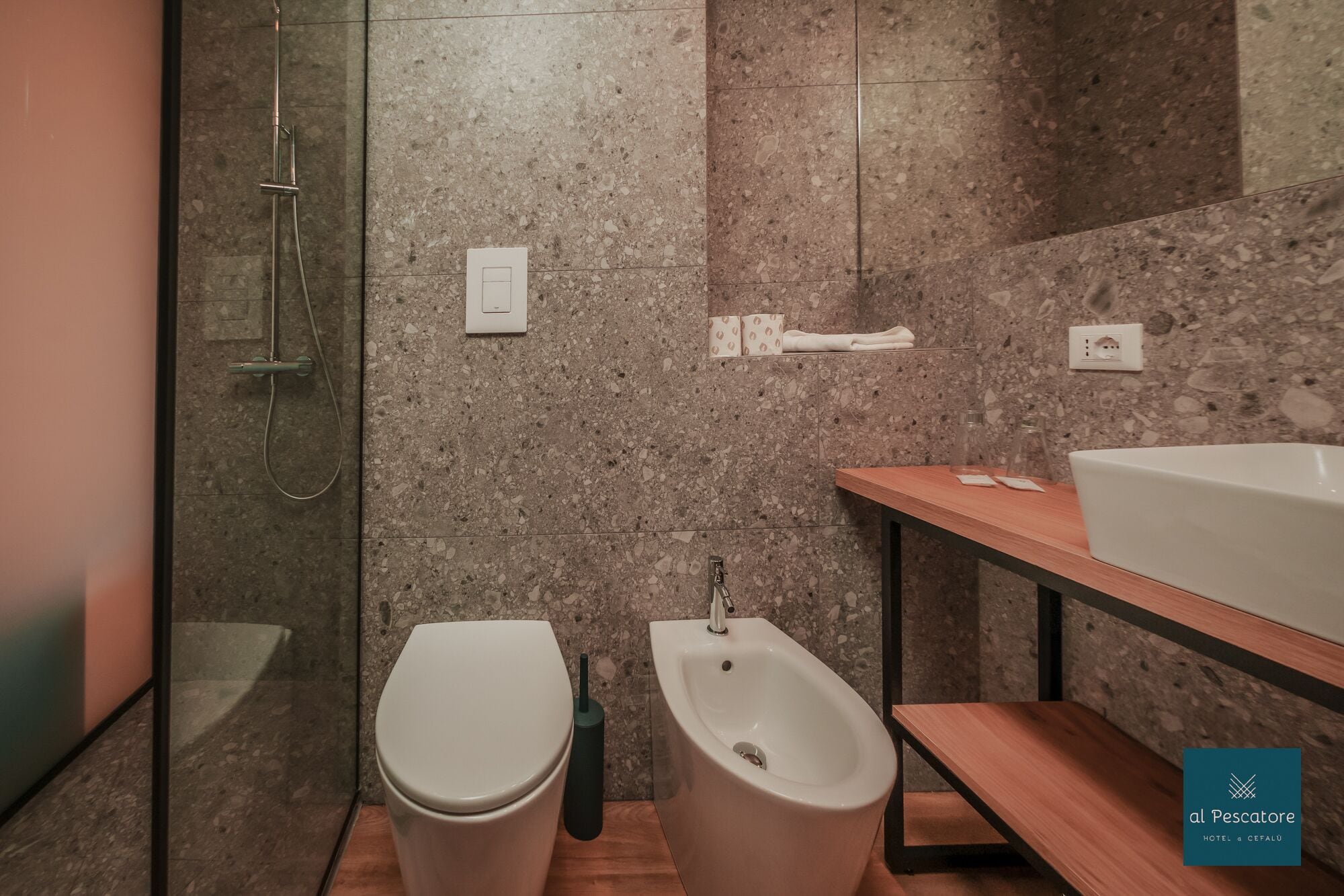 A modern bathroom with a shower, toilet, bidet, and a wooden vanity with a sink.