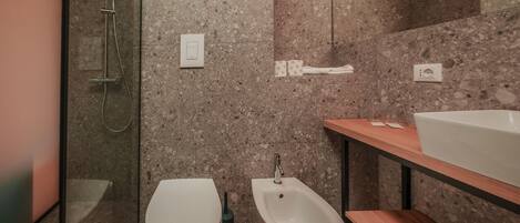 A modern bathroom with a shower, toilet, bidet, and a wooden vanity with a sink.