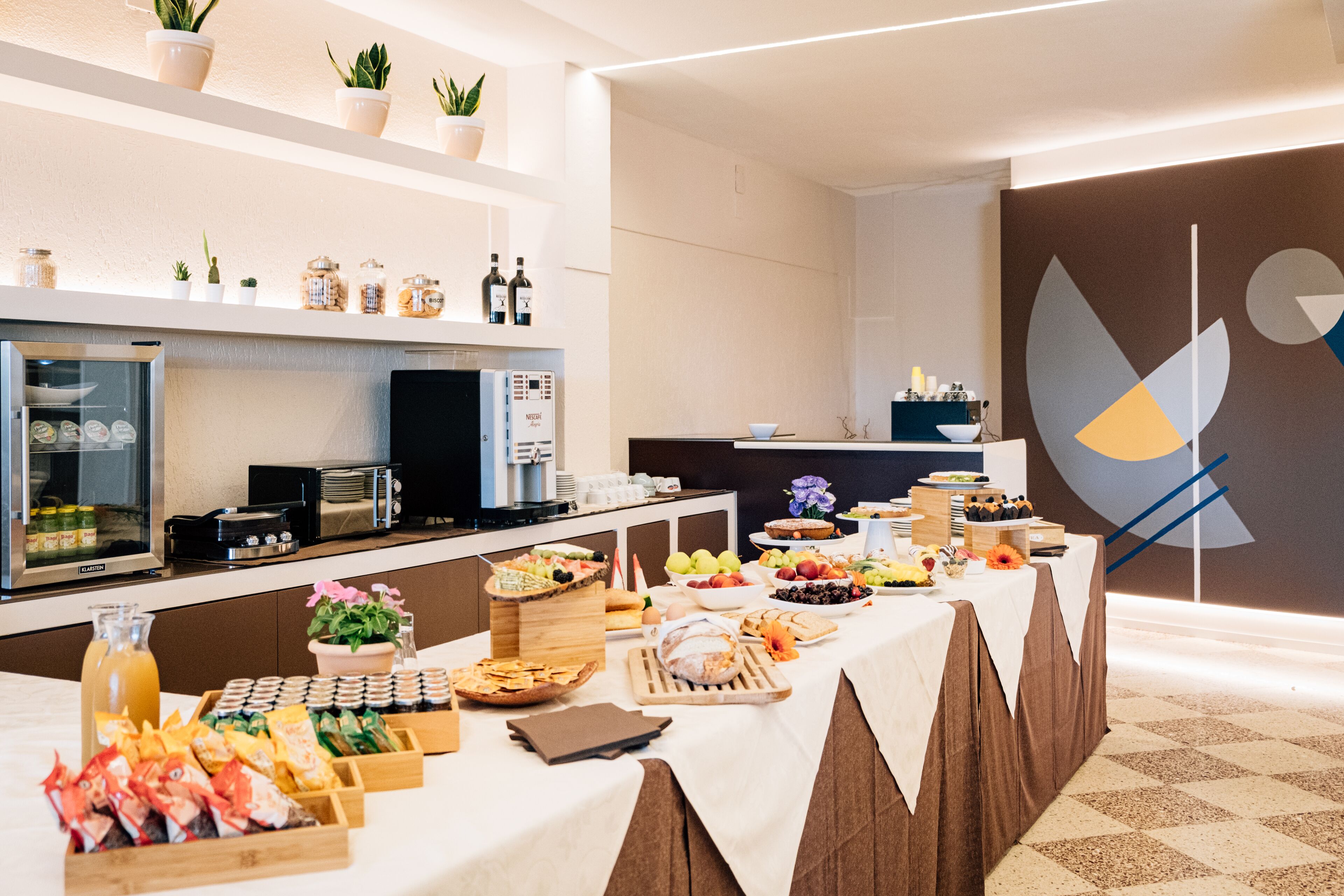 Una mesa de buffet con diversos alimentos, un refrigerador y una cafetera.