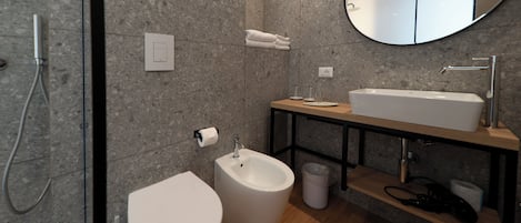 A modern bathroom with a bidet, toilet, sink, and mirror.