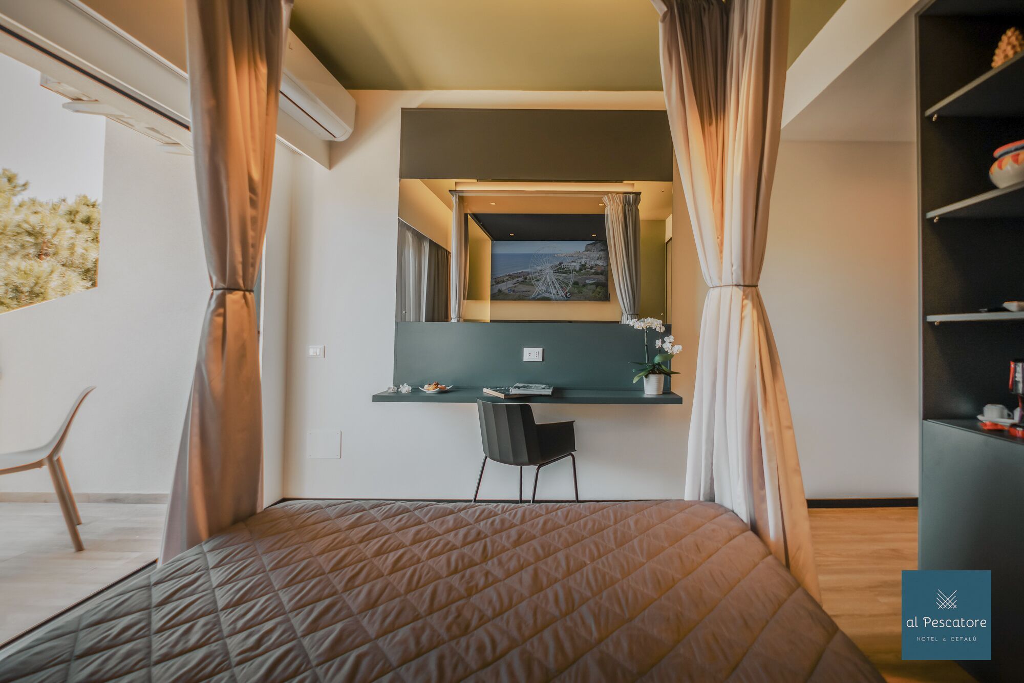 Ein Schlafzimmer mit Bett, Schreibtisch, Stuhl, Spiegel und Blick ins Freie.