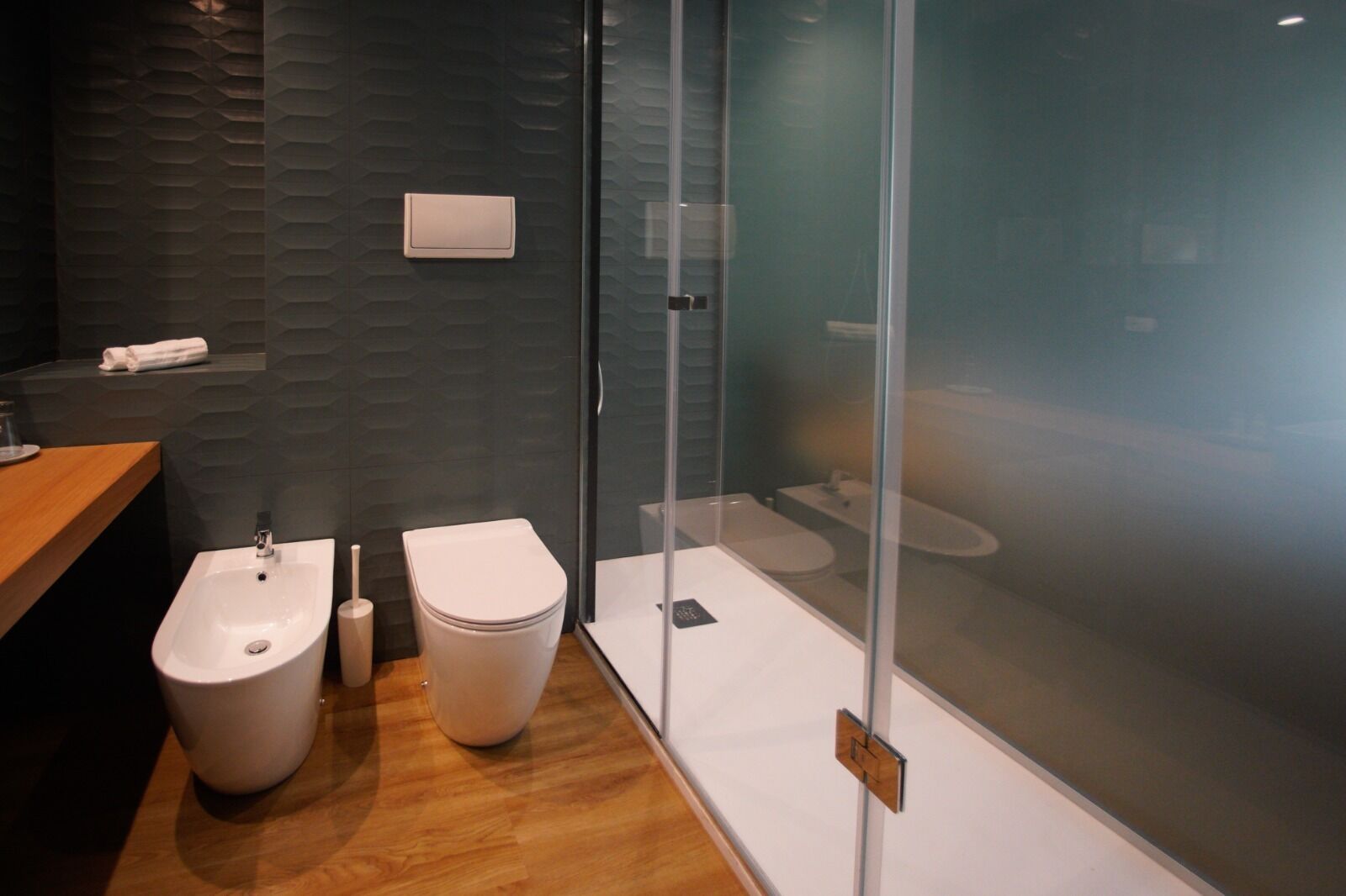A modern bathroom with a bidet, toilet, and glass shower enclosure.