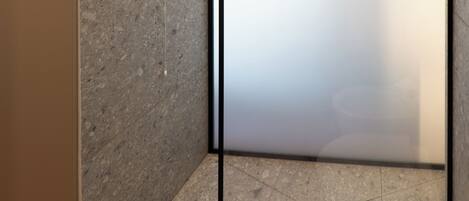 A modern shower area with a glass door, tiled walls, and a visible drain.