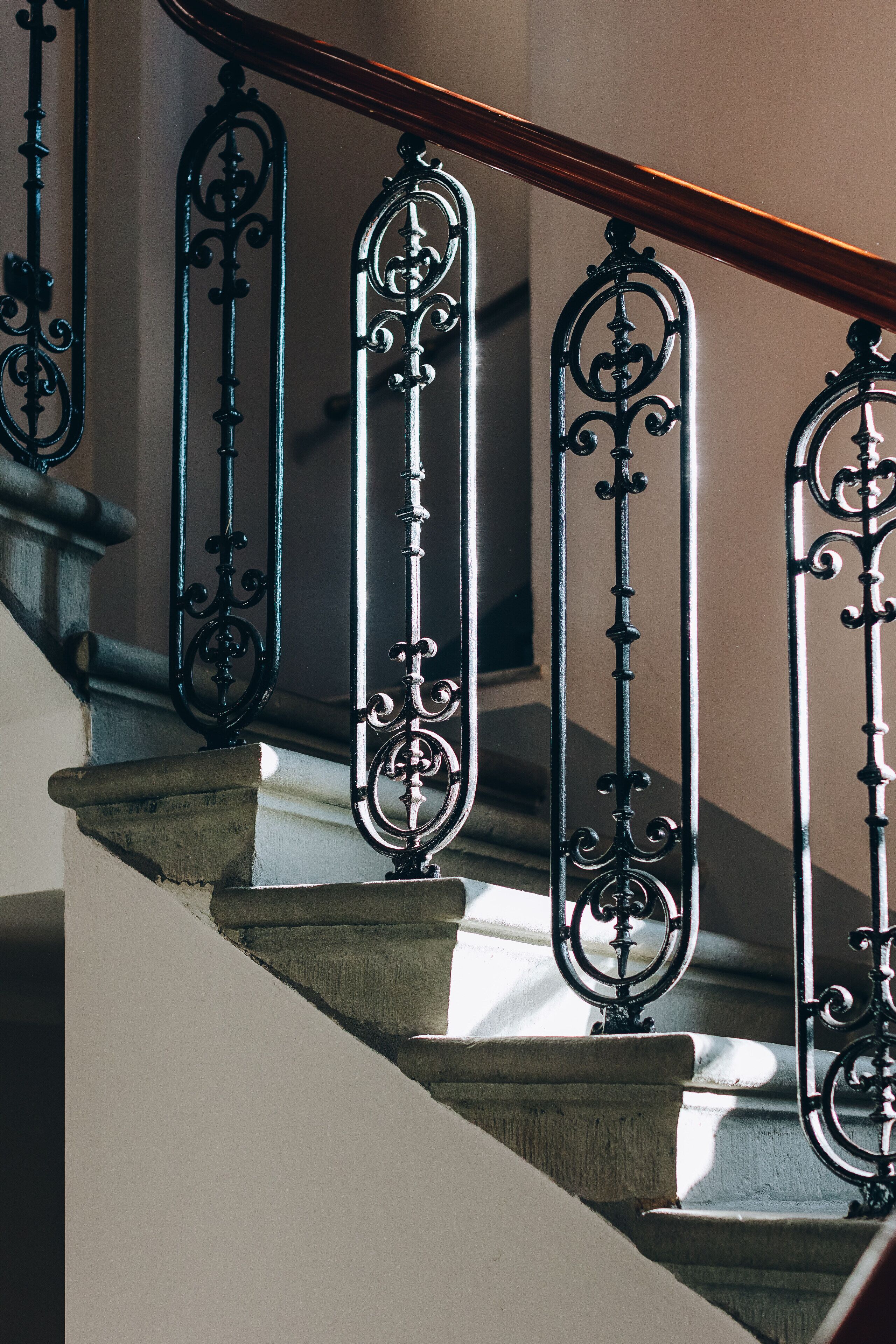 Una escalera con barandillas de metal negro ornamentado y baranda de madera.