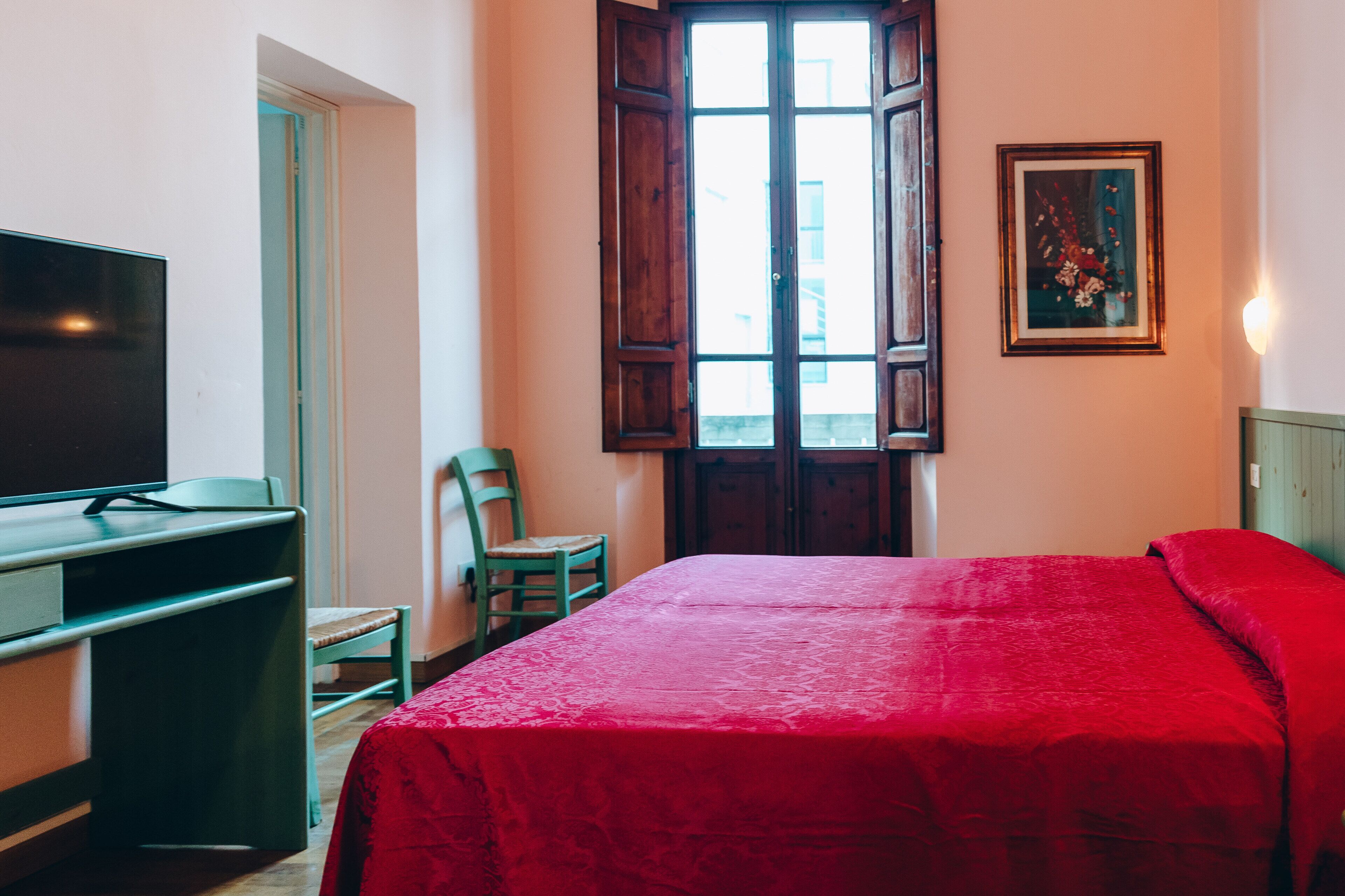 A room with a bed, a desk, a chair, and a television.