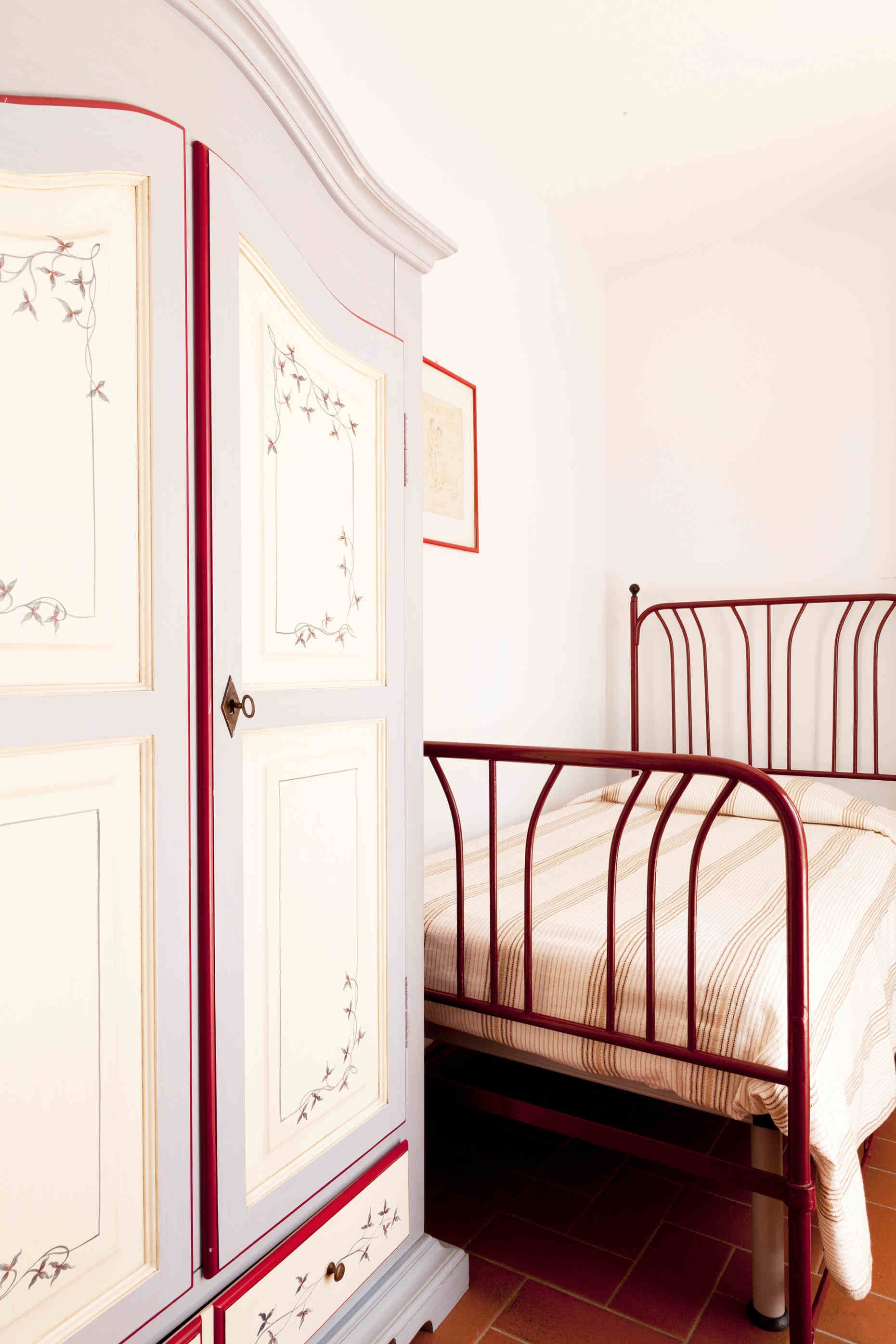 A bedroom with a white wardrobe and a metal bed frame.