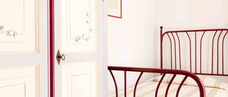 A bedroom with a white wardrobe and a metal bed frame.