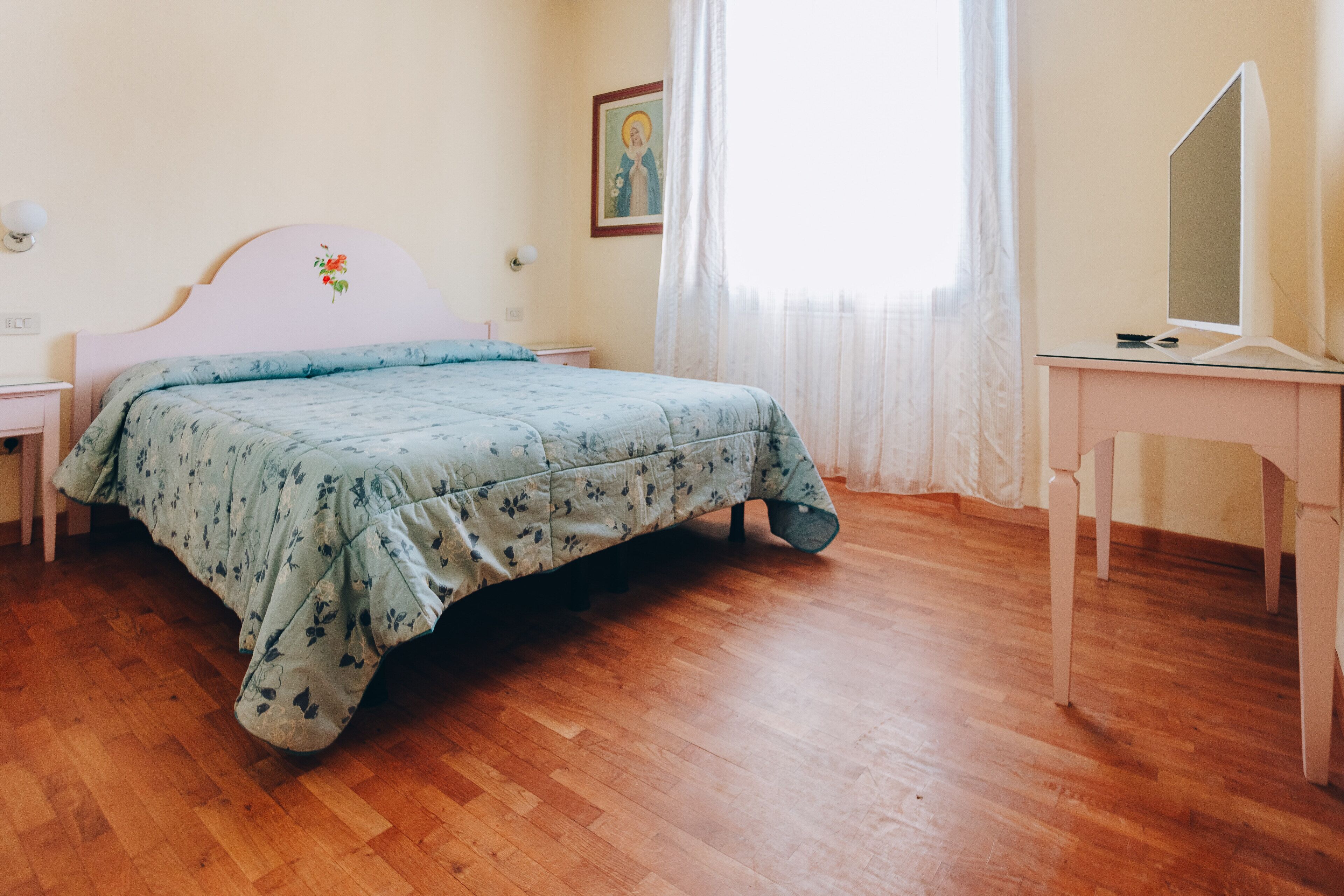 Un dormitori amb un llit, un escriptori i una cadira.