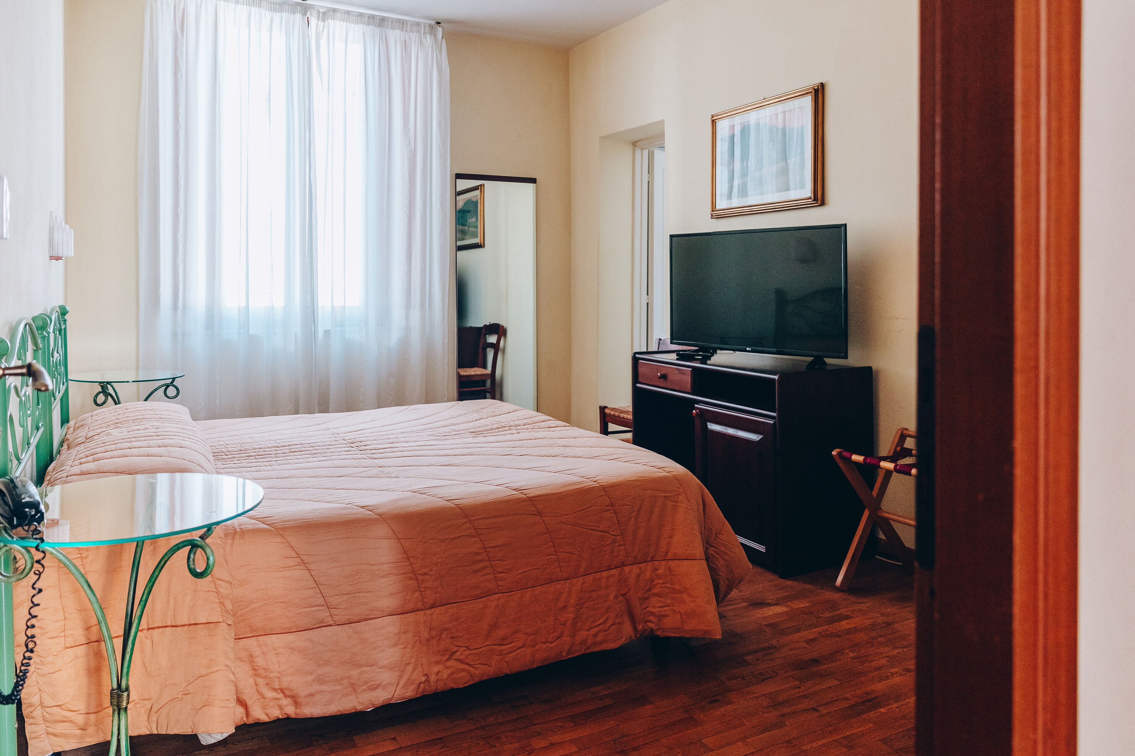 Una habitación de hotel con cama, televisión, escritorio y una silla.