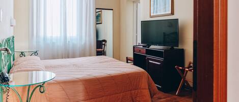Una habitación de hotel con cama, televisión, escritorio y una silla.