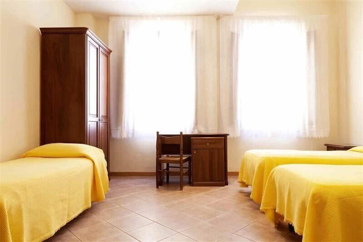 Una habitación con dos camas, un escritorio y un armario.