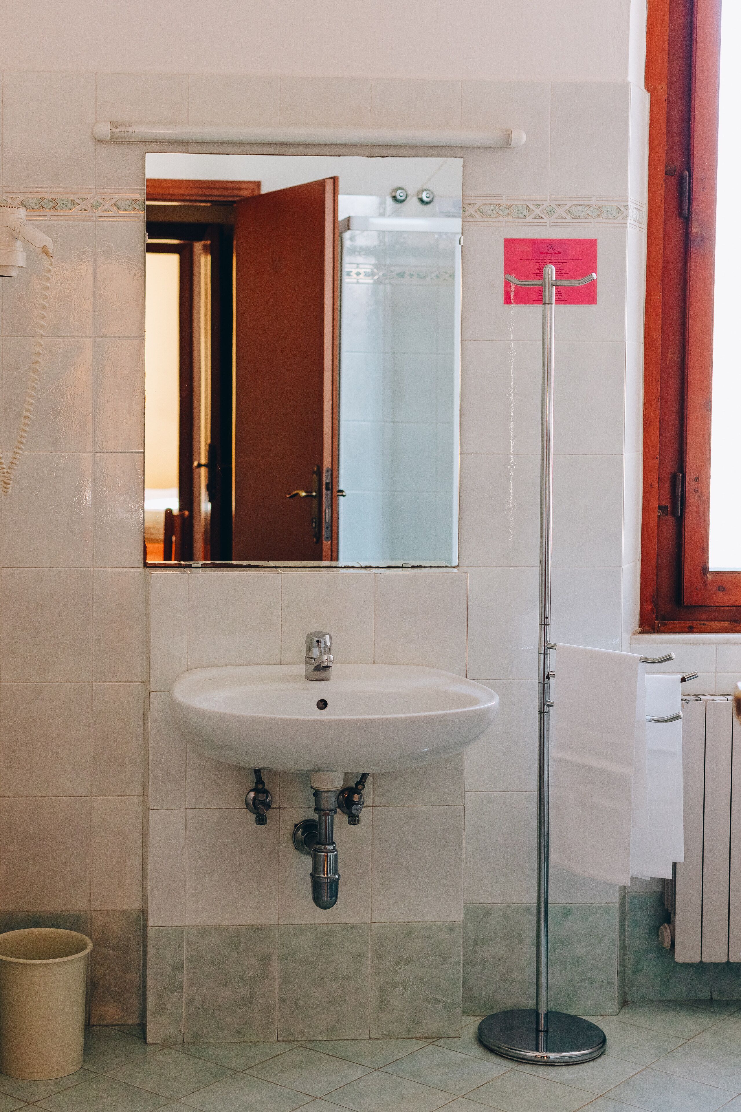 Un baño con un lavamanos blanco, un espejo y un toallero.