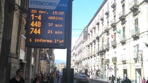 A bus stop with a digital display showing bus arrival times. - Rubens (Catania)