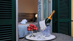 Une chambre avec un lit, un plateau avec des fraises, du champagne et des verres.