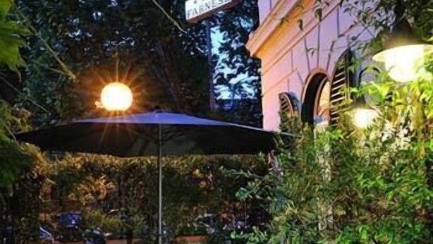 Un espace extérieur aménagé en terrasse, avec des tables et des chaises, entouré de plantes en pot et d’un panneau de signalisation.