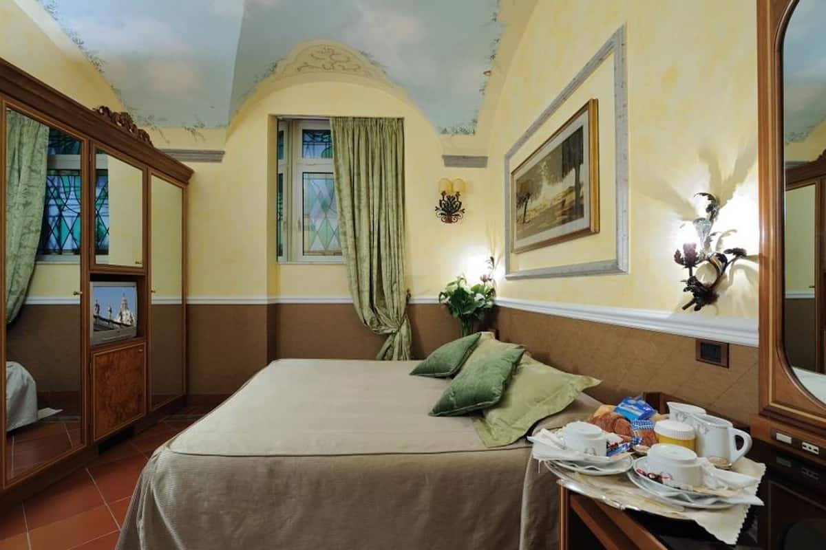 Ein Hotelzimmer mit einem Bett, einem Fernseher, einem Gemälde und einem Tisch mit Frühstücksangeboten.