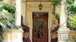 L’entrée d’un hôtel, avec une porte en bois, un escalier et des plantes en pot.