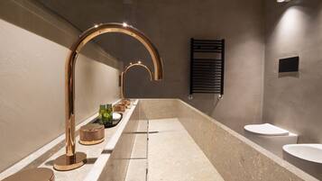 A modern bathroom with a large bathtub, a gold faucet, and a black towel rack.