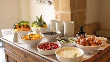 A buffet table with various food items including fruits, vegetables, and eggs.