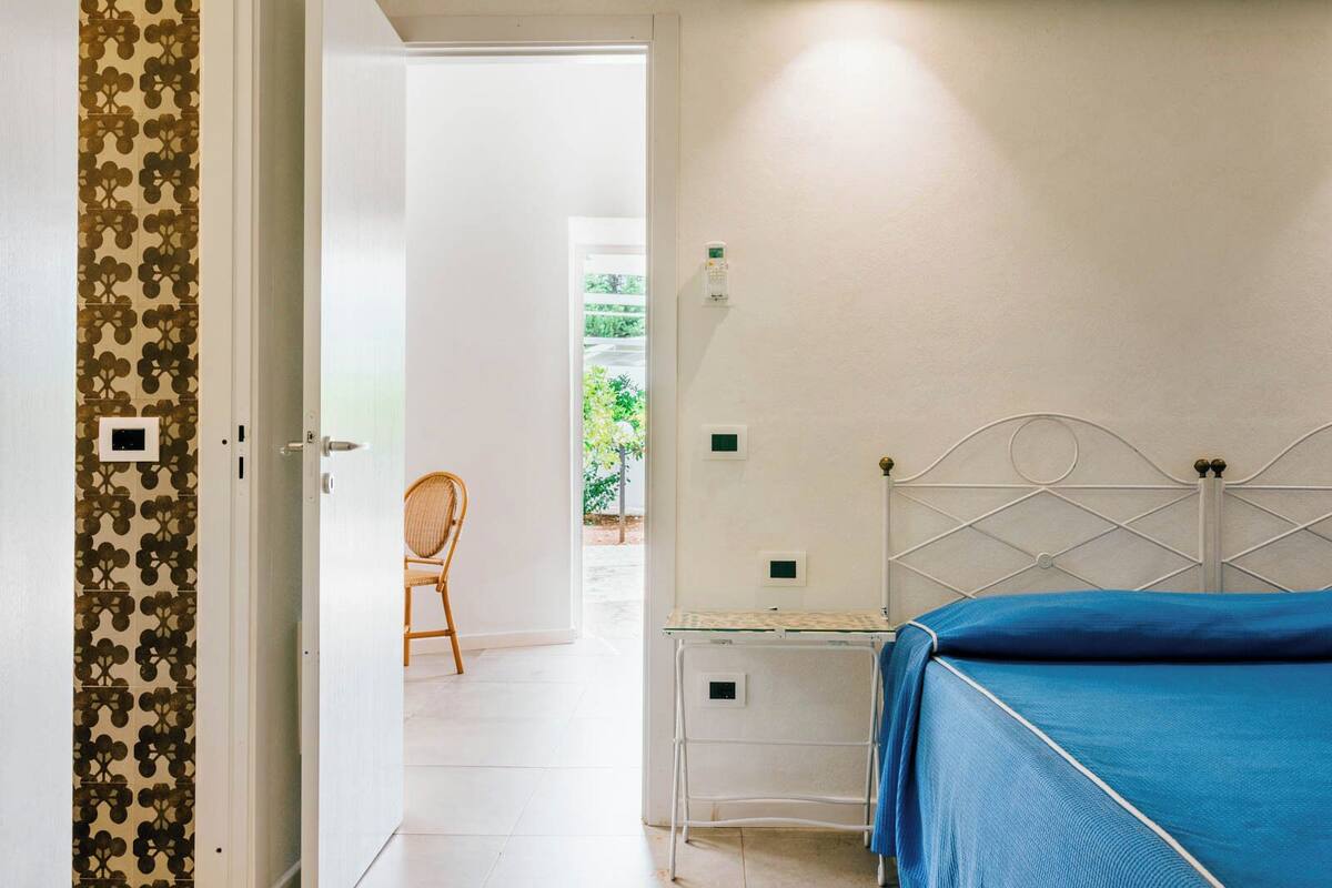 A bedroom with a bed, a chair, and a door leading to a balcony.