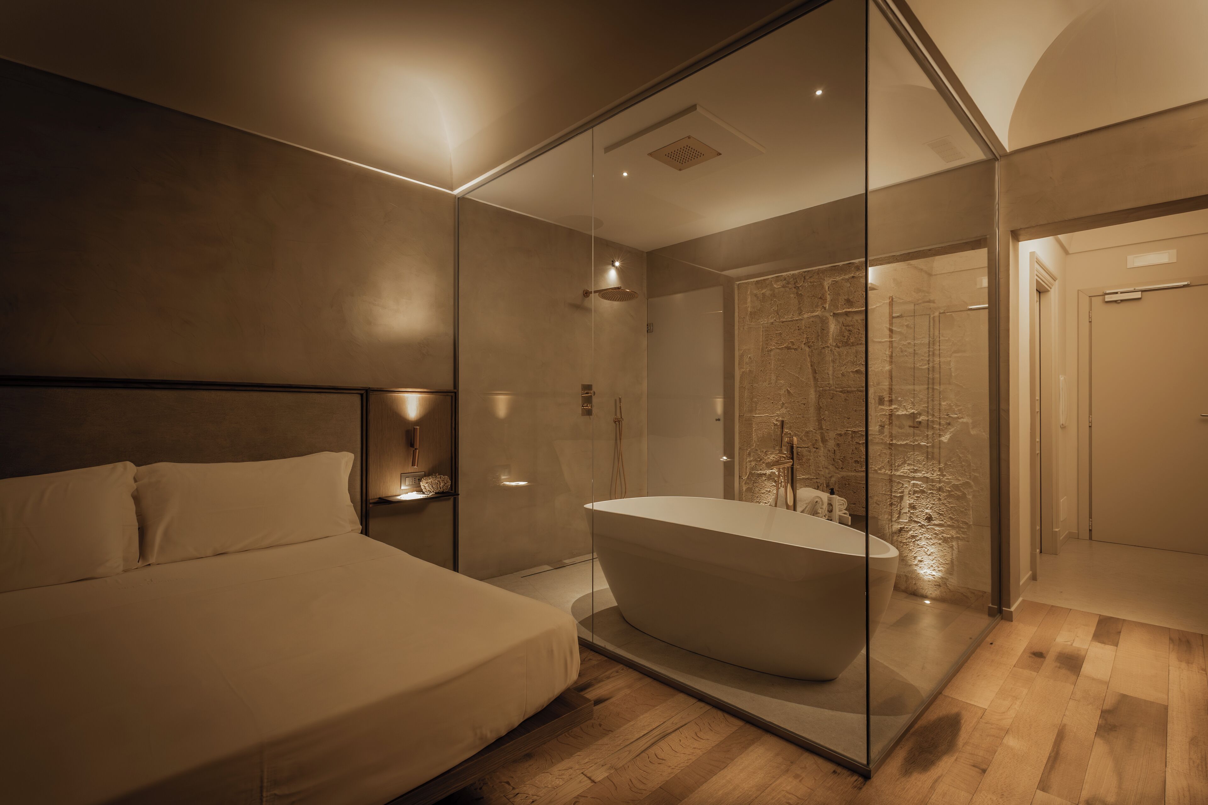 Un baño moderno con una bañera independiente, ducha con cerramiento de vidrio y suelo de madera.