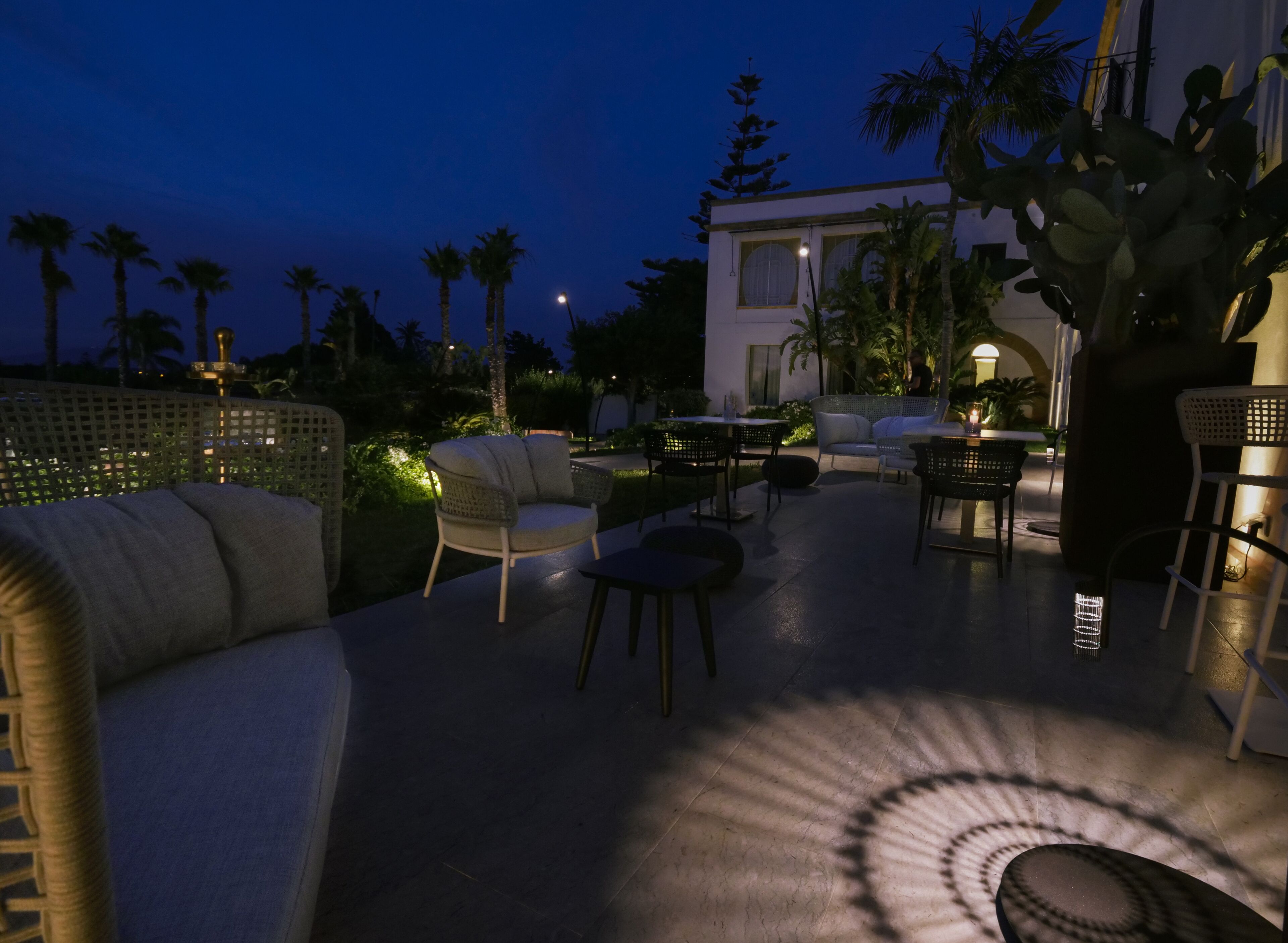Un patio al aire libre con arreglos de asientos, incluyendo sofás y sillas, y una mesa de comedor.