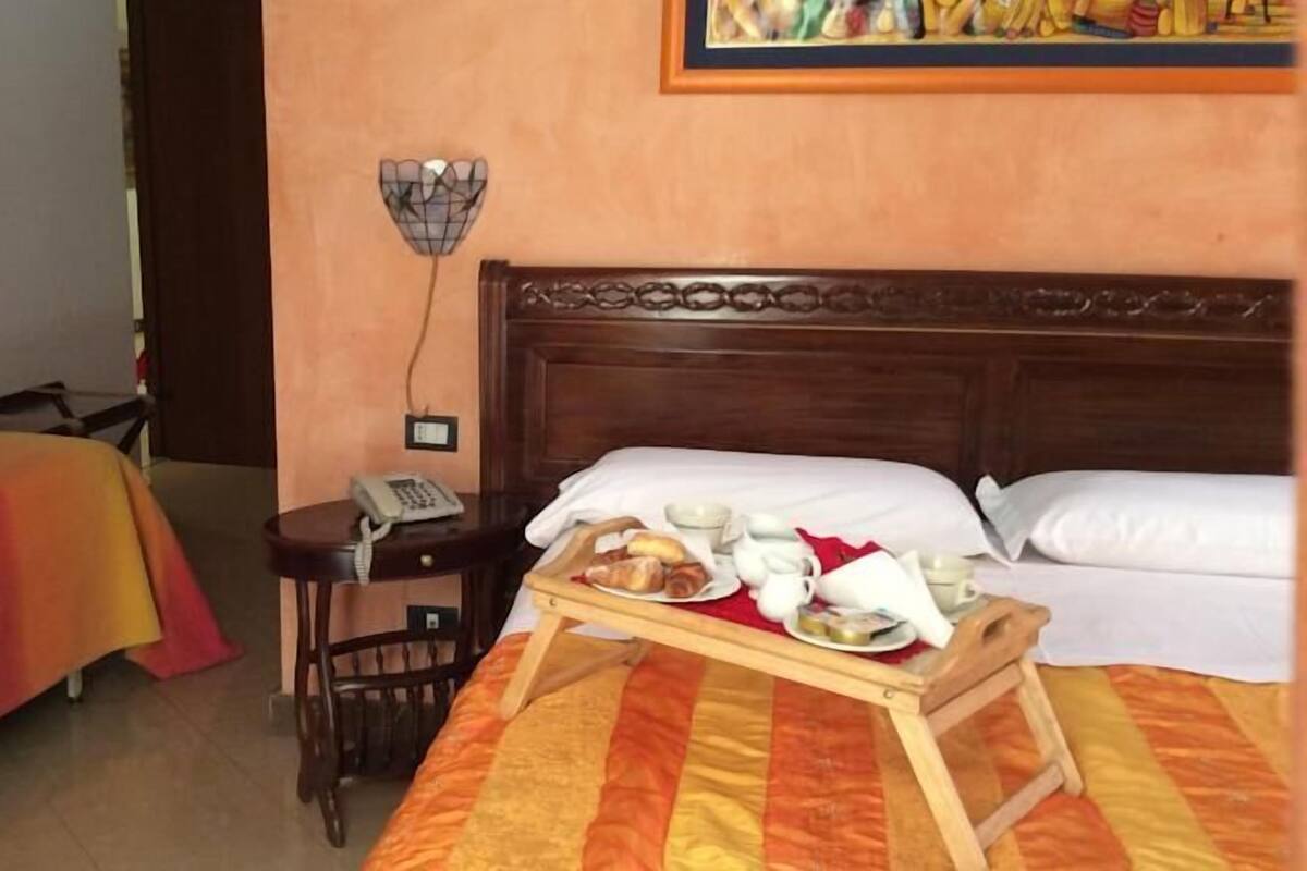 Habitación de hotel con dos camas, un escritorio pequeño con un teléfono y una bandeja con alimentos para el desayuno.