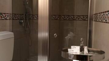 A bathroom with a glass-enclosed shower, a toilet, and a sink with toiletries.