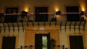 Un edificio con espacio comercial en la planta baja y balcones con barandillas en los niveles superiores.