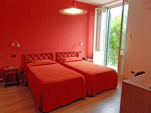 A room with two beds, a wooden floor, a balcony, and a large window. - Hotel Villa Archirafi (Palermo)