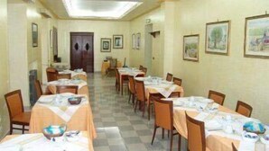 A dining area with tables set for meals, chairs, and framed pictures on the walls. - Hotel Villa Archirafi (Palermo)