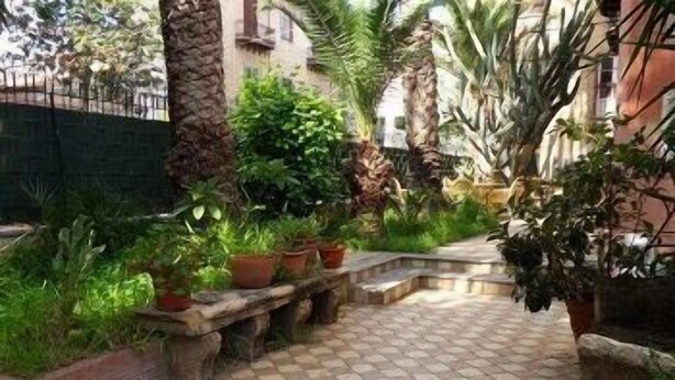 A paved courtyard with potted plants and a stone bench. - Hotel Villa Archirafi (Palermo)