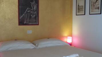 Ein Hotelzimmer mit einem Bett, Kissen, einem Nachttisch mit Lampe und drei gerahmten Bildern an der Wand.